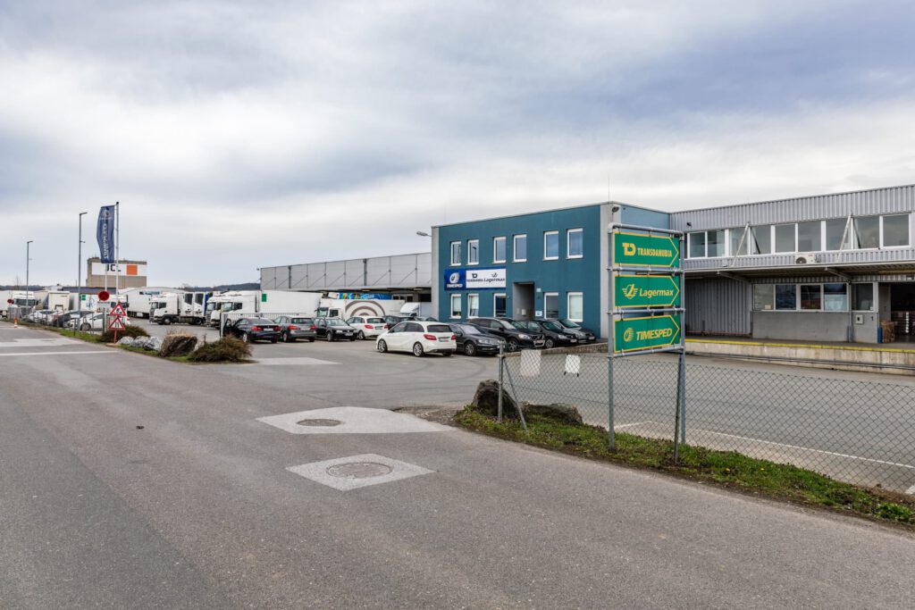 Gewerbeimmobilie Bahnhofstraße 103 mit mehreren geparkten Fahrzeugen und blauer Gebäudefassade.