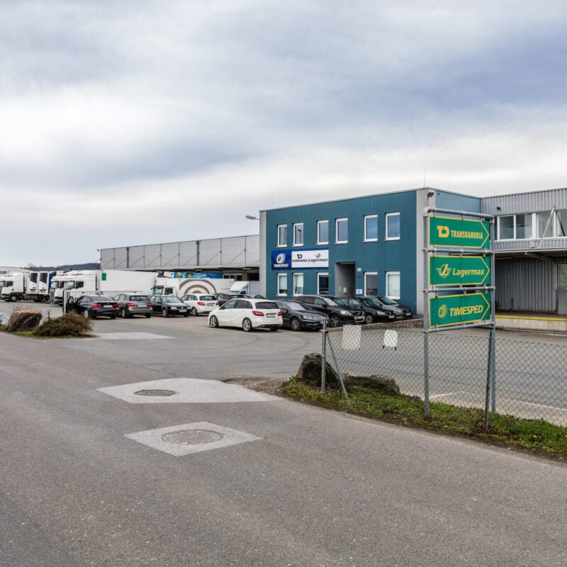 Gewerbeimmobilie Bahnhofstraße 103 mit mehreren geparkten Fahrzeugen und blauer Gebäudefassade.