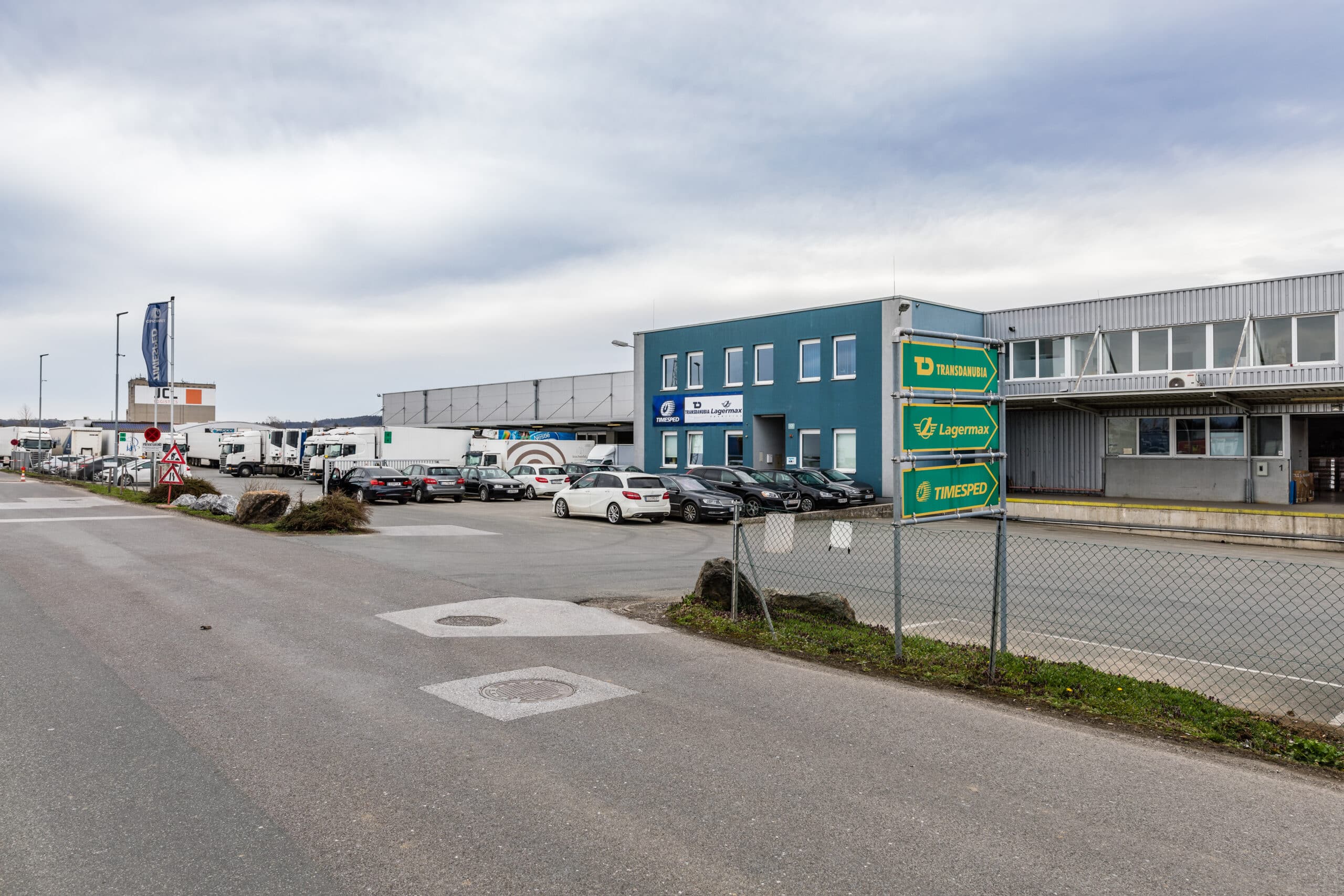 Gewerbeimmobilien an der Bahnhofstraße 103 mit mehreren Firmen und Parkplatz.
