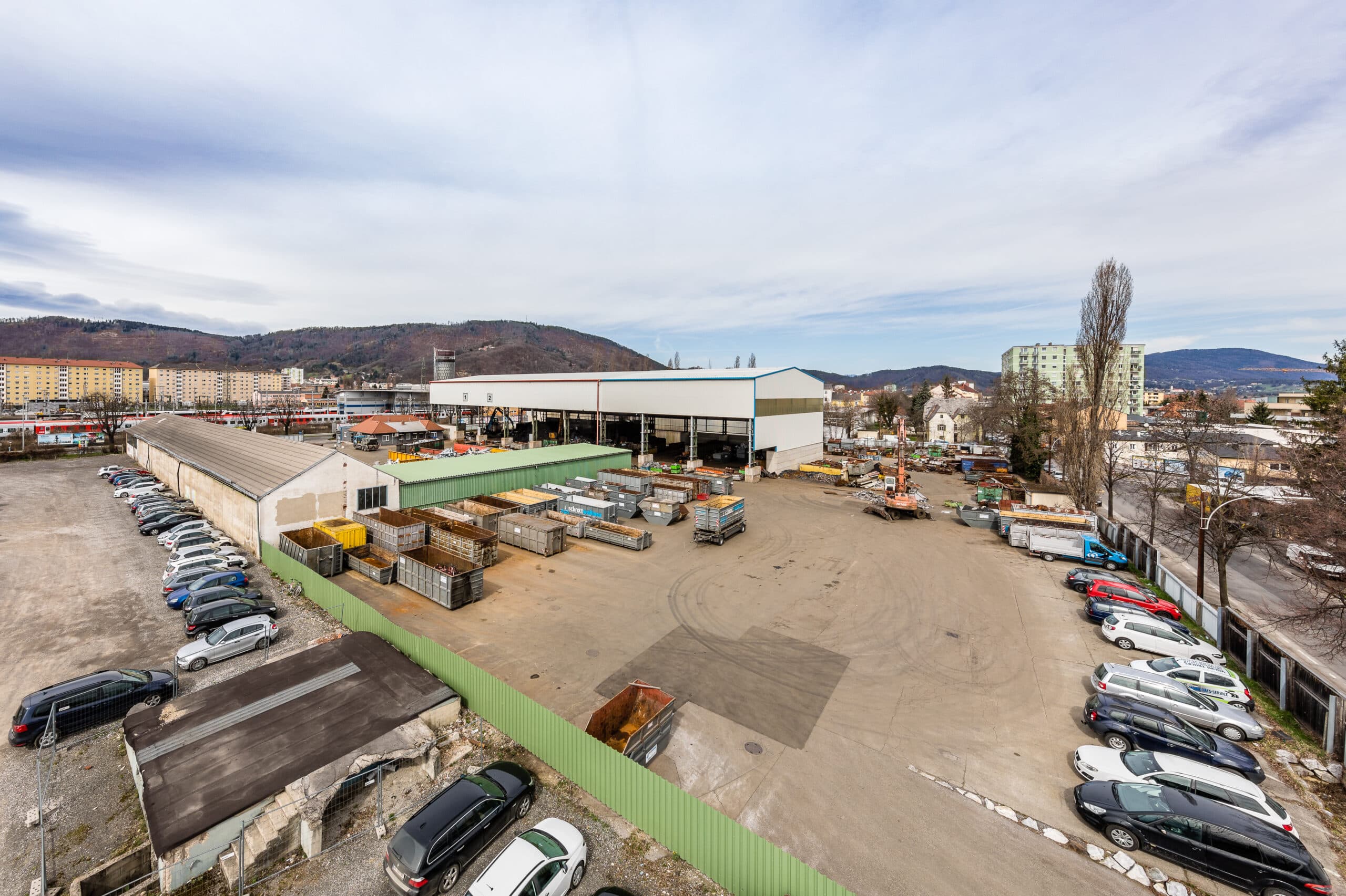 Gewerbeimmobilie mit großem Parkplatz und Lagerfläche in urbaner Umgebung.