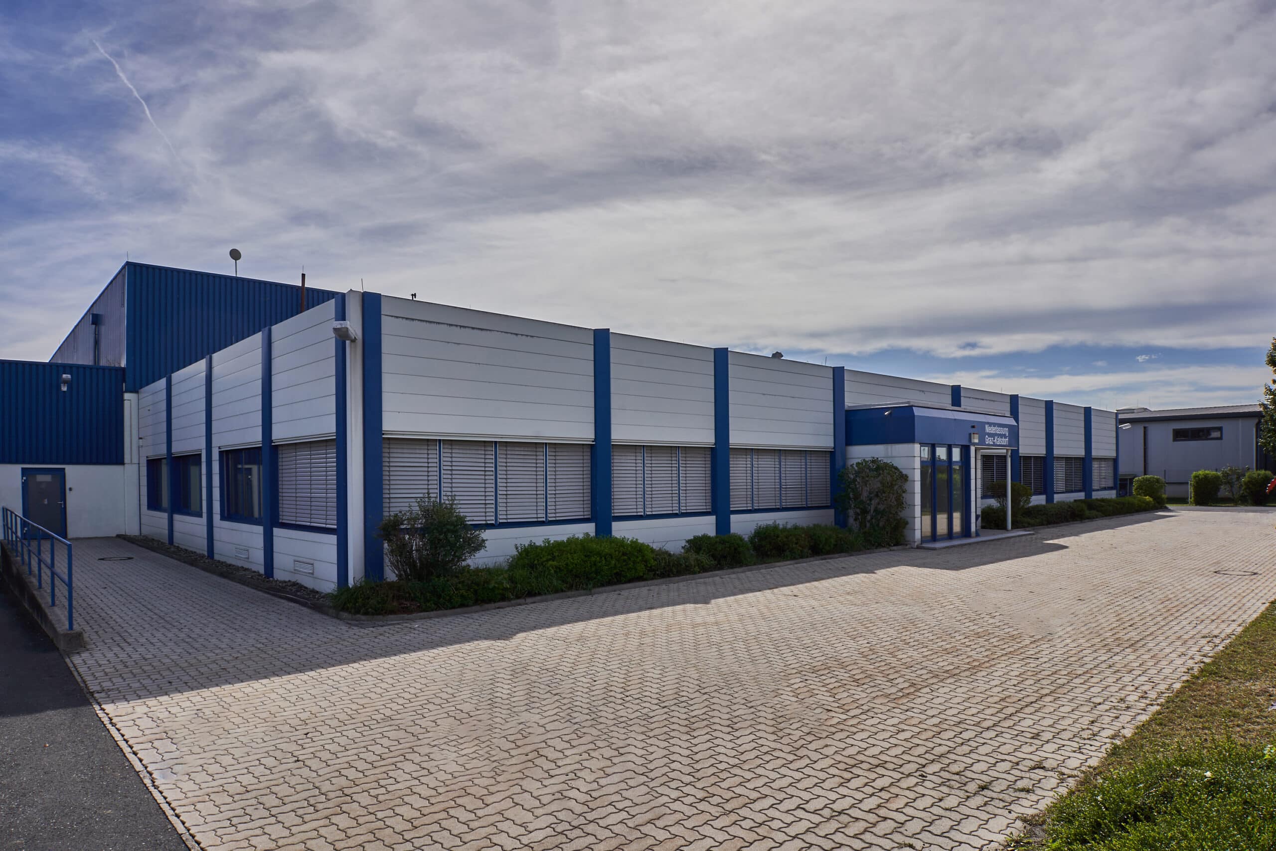 Moderner Industriekomplex mit blauen Akzenten und großzügiger Parkplatzfläche bei Bahnhofstraße 112.