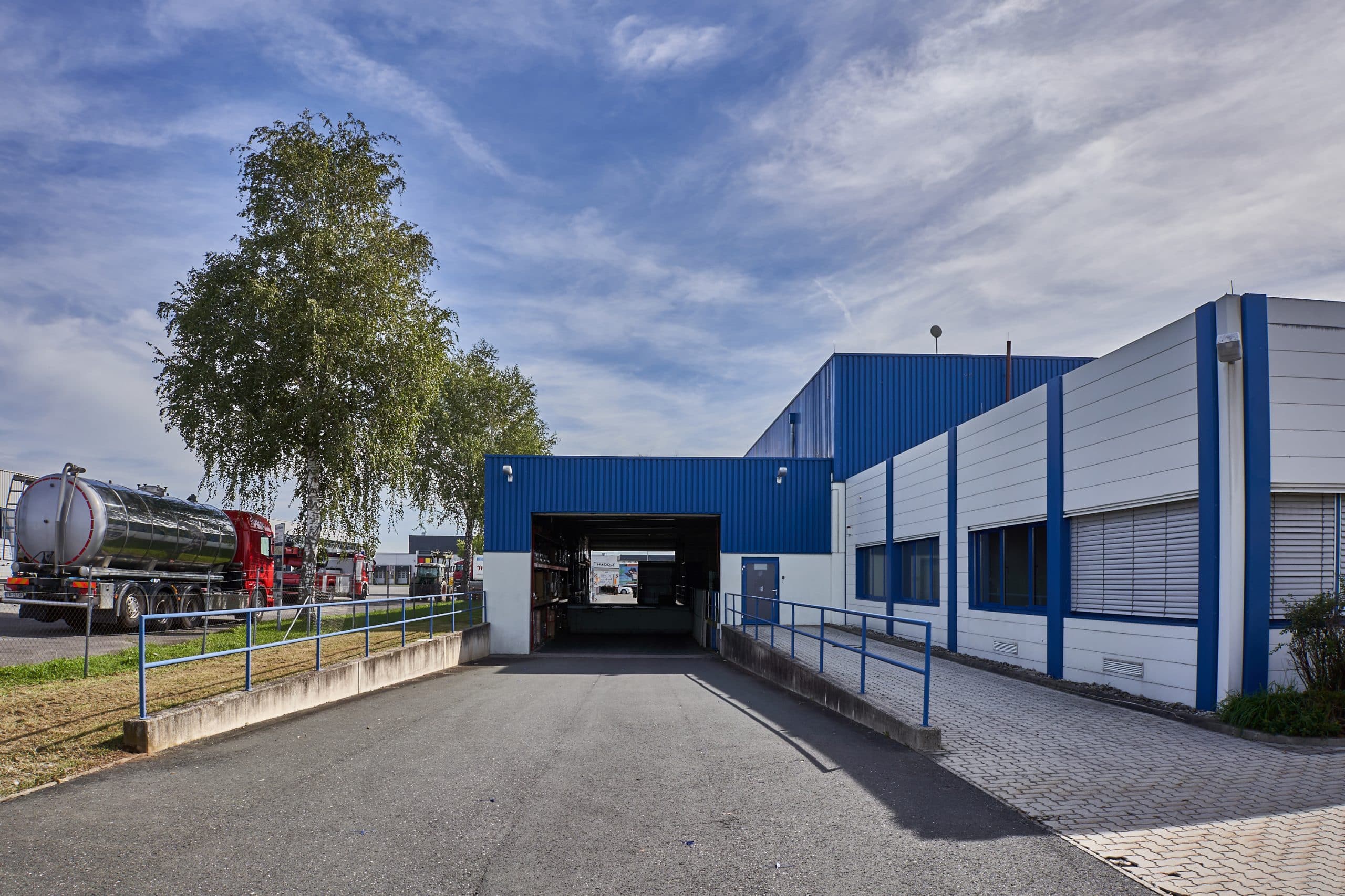 Gewerbeimmobilie mit blau-weißer Fassade und Lkw-Zugang bei Bahnhofstraße 112.