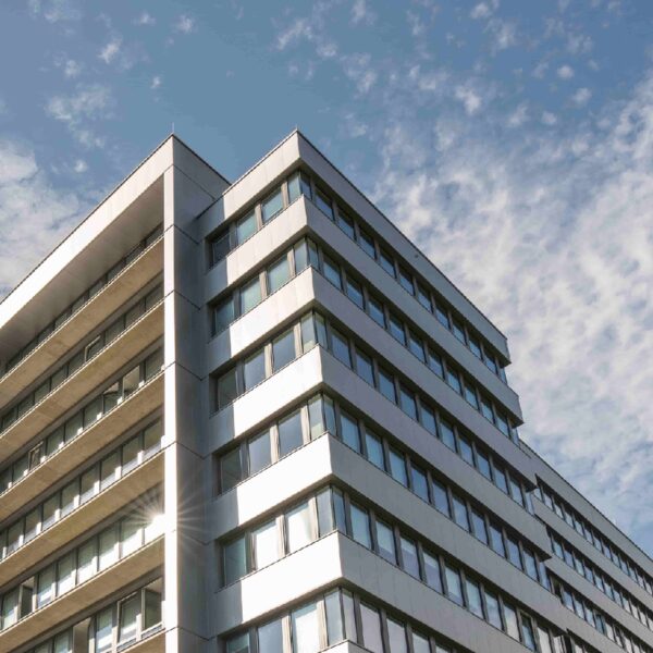 Moderne mehrstöckige Fassade eines Bürogebäudes vor bewölktem Himmel.