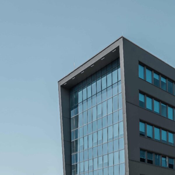 Modernes Bürogebäude mit Glasfassade vor blauem Himmel.